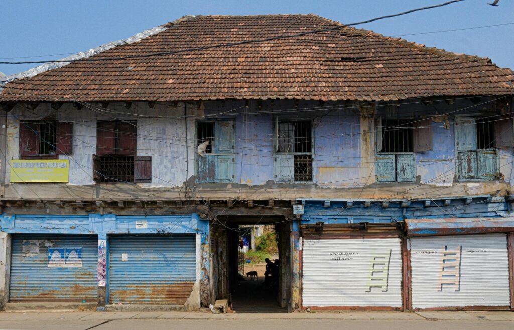 A rustic old building facade with blue shutters in Kochi, Kerala, India.