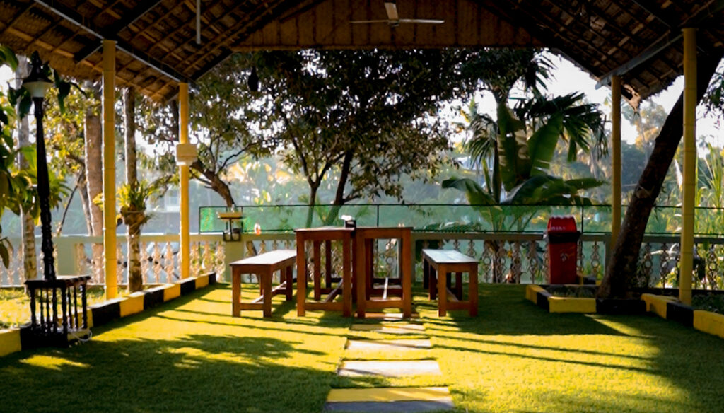 open sitout area with wooden seating and traditional roof pavilion at homestay kochi