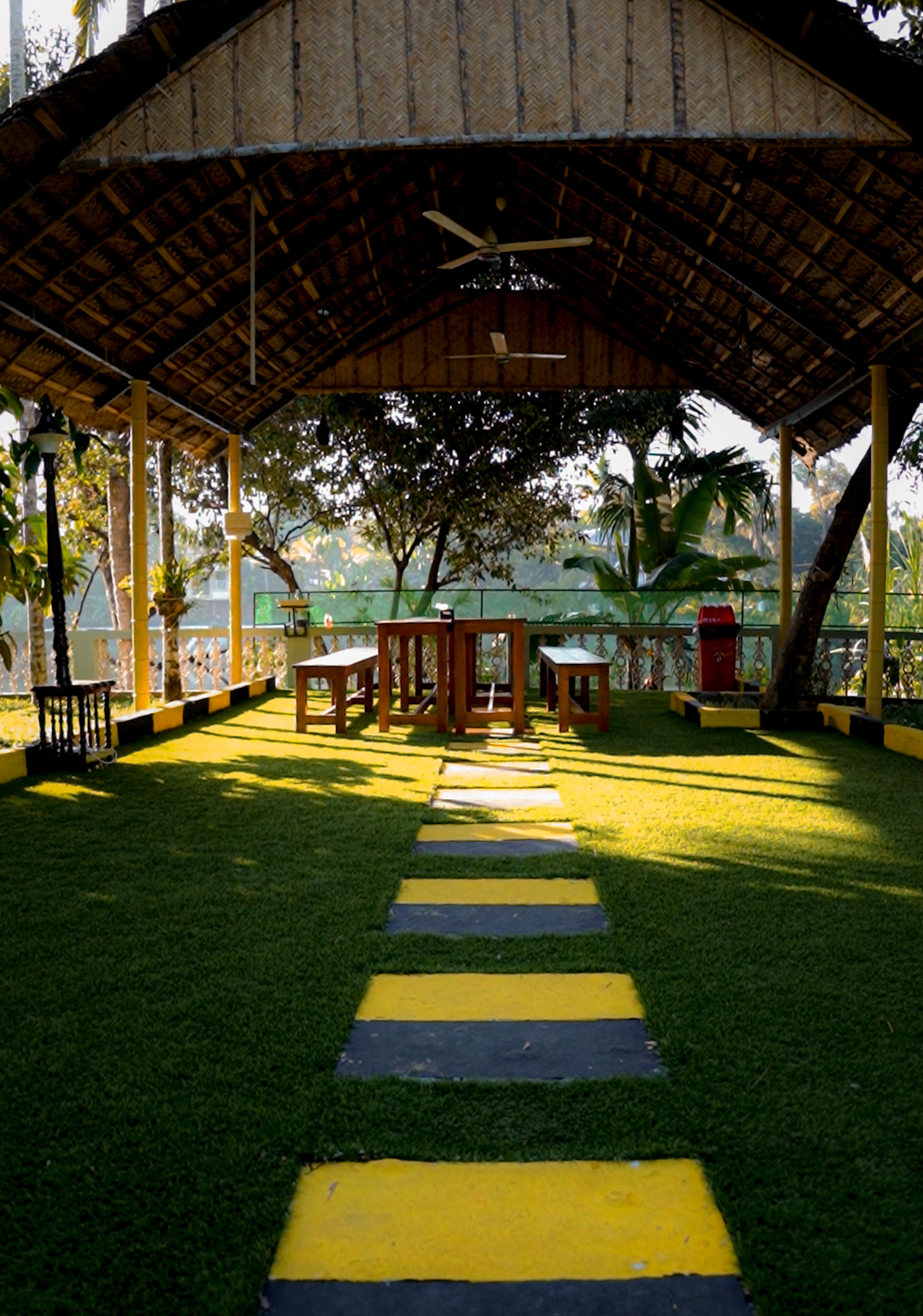 open sitout area with wooden seating and traditional roof pavilion at homestay kochi
